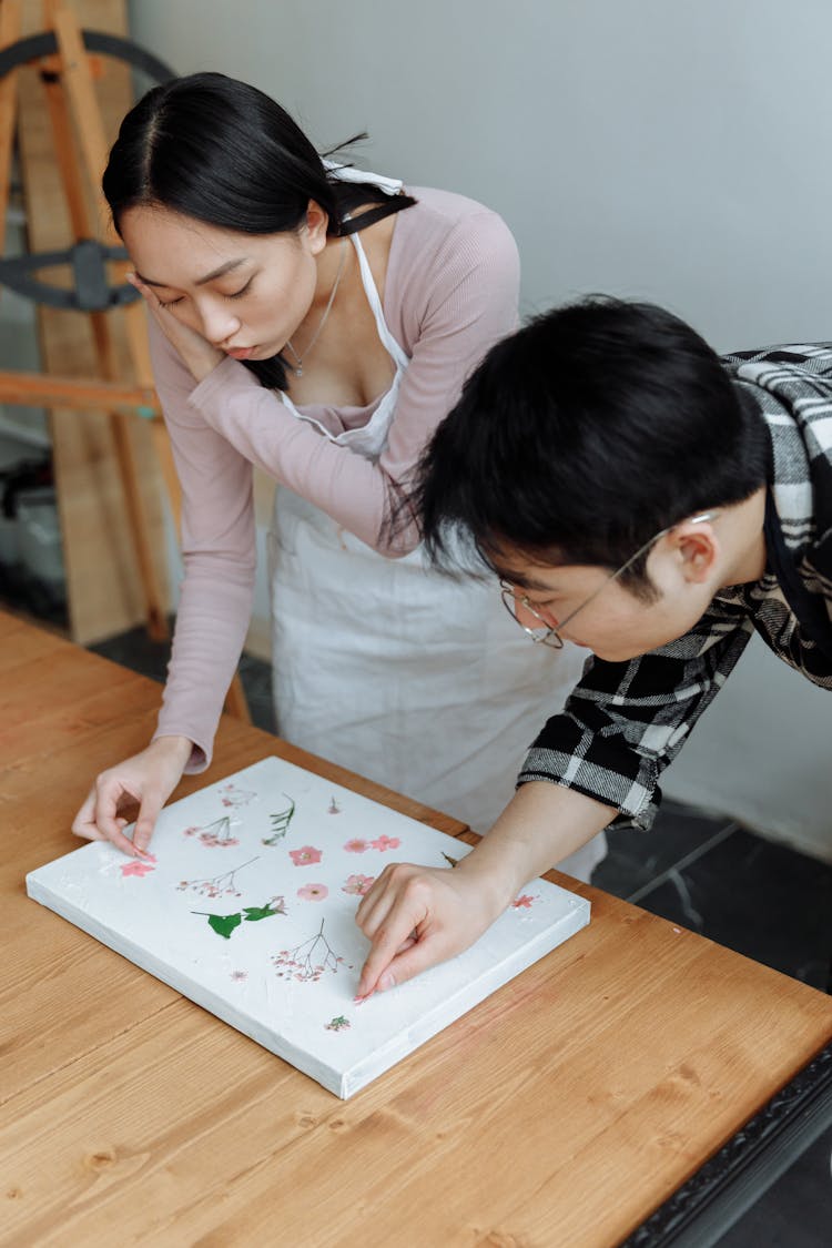 Man And Woman Decorating Board With Flowers