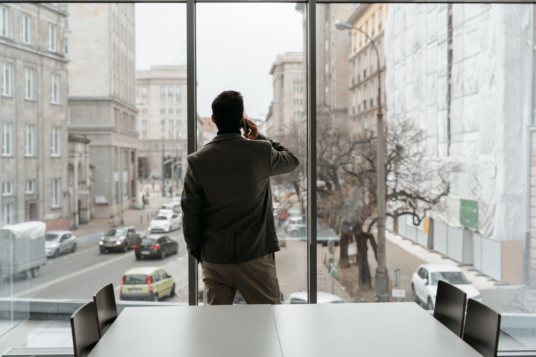 Professional man making a phone call while looking out of an urban office window.