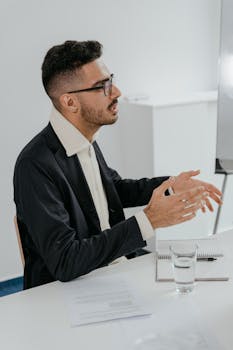 Businessman in a black suit actively engaged in an office meeting, expressing ideas.