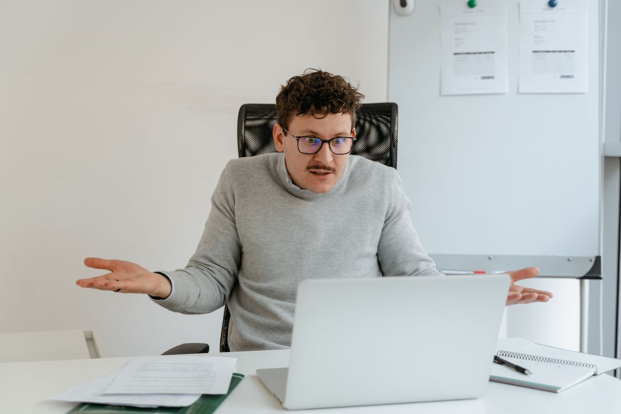 Confused man gesturing at his laptop screen during a video call