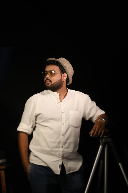 Bearded Indian man in aviator sunglasses leaning on tripod