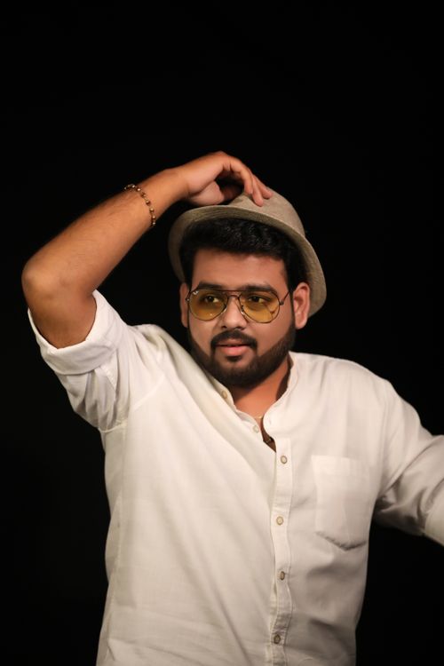 Free Young bearded ethnic male in trendy sunglasses and hat looking away on black background Stock Photo