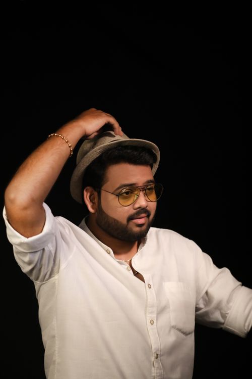 Free Young bearded ethic male in stylish hat touching head and looking away on black background Stock Photo