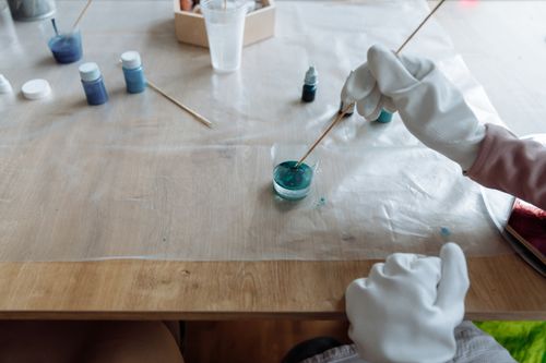 Free Close-up of a person mixing blue paint with a stick in an art studio setting. Stock Photo