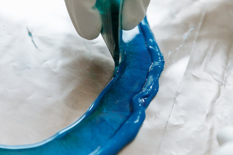 A Person Pouring Resin On A Mold