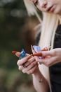 Unrecognizable female with manicured hands and blond hair examining bright uncut opals in hands while standing on blurred background on street