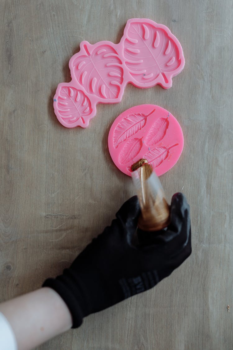 A Person Pouring Resin On A Mold