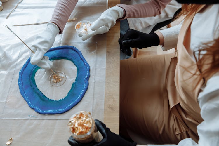 A Person Applying Gold Flakes In A Resin Art