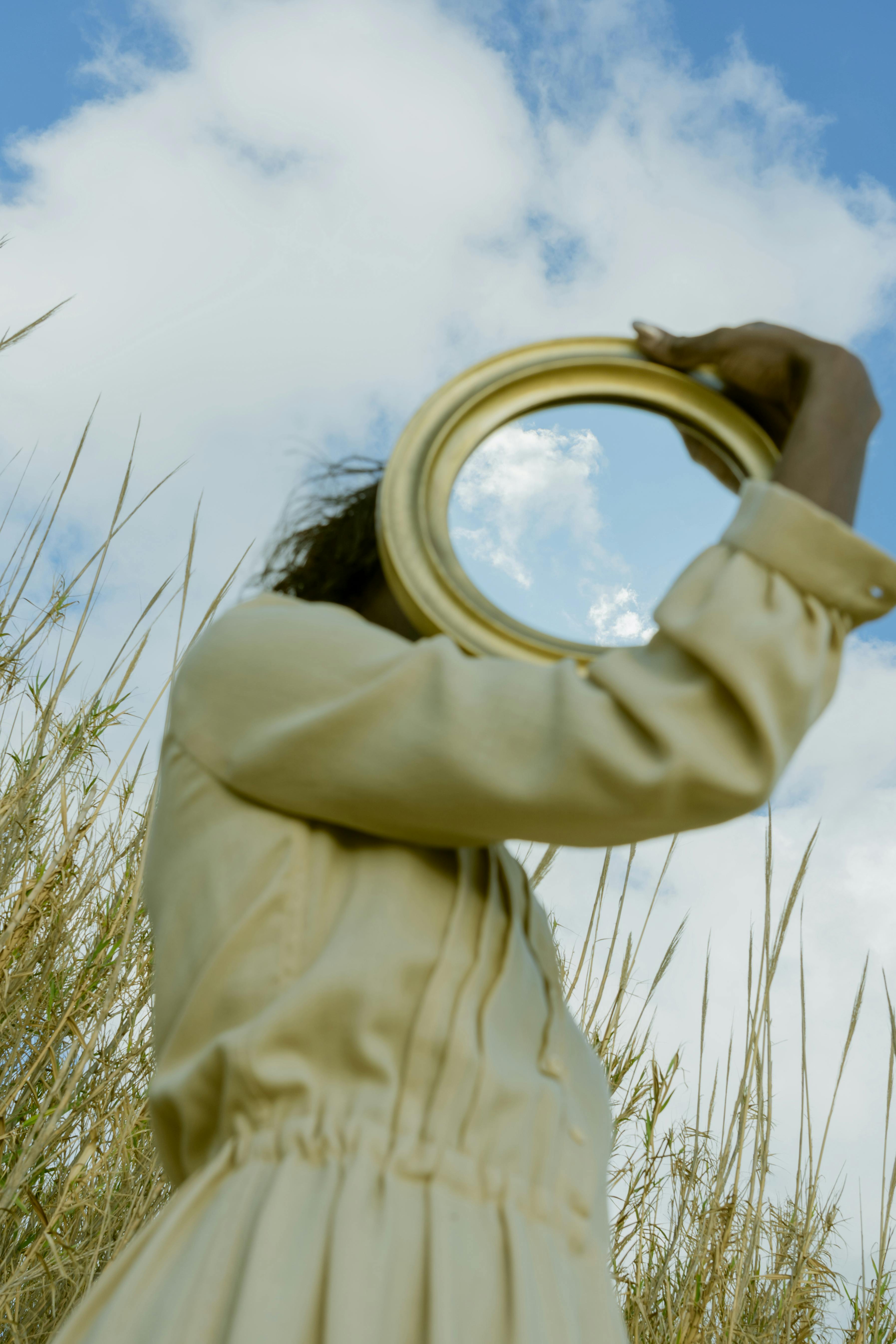 woman holding circular mirror in a field