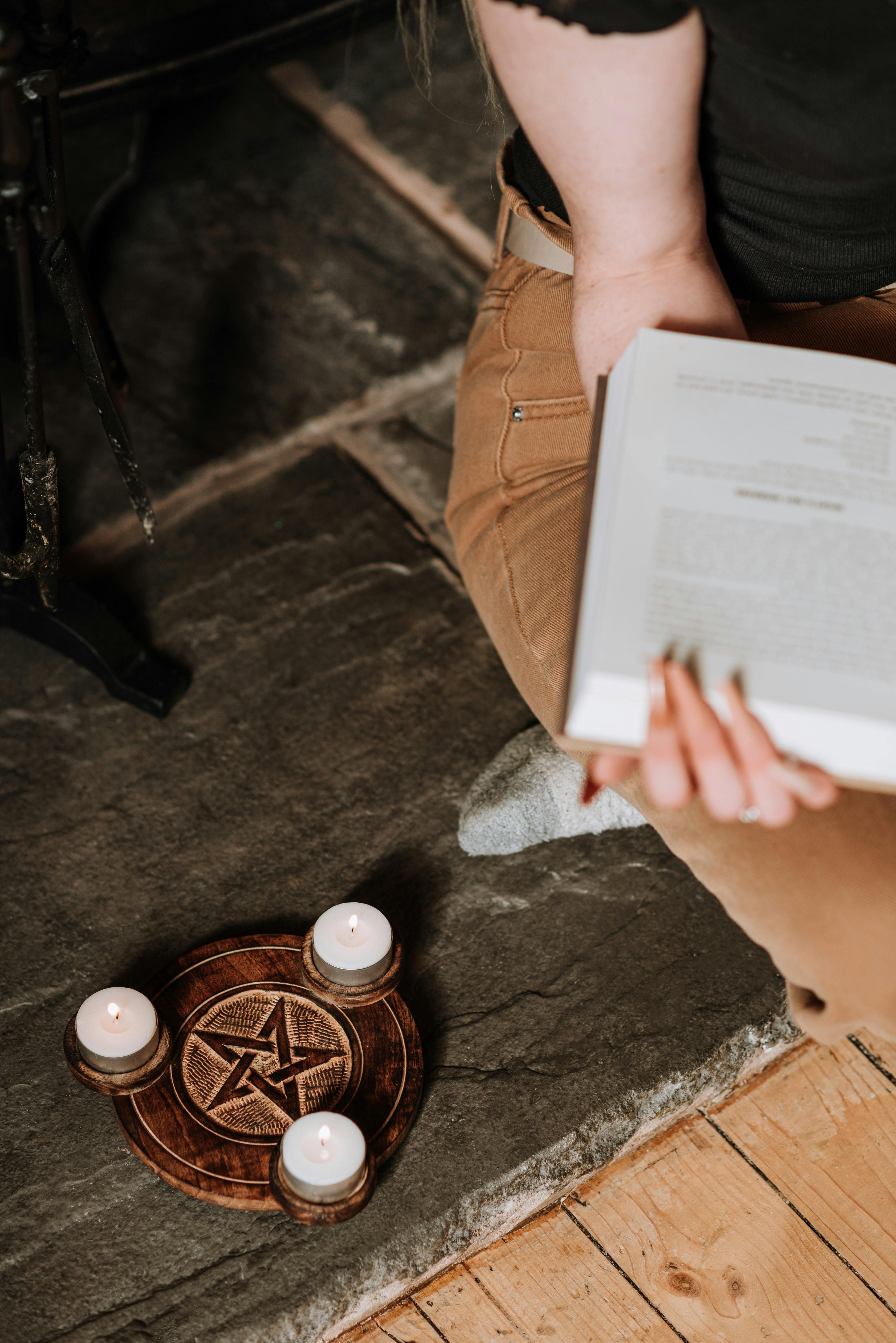 mysterious woman with book near pentagram with candles