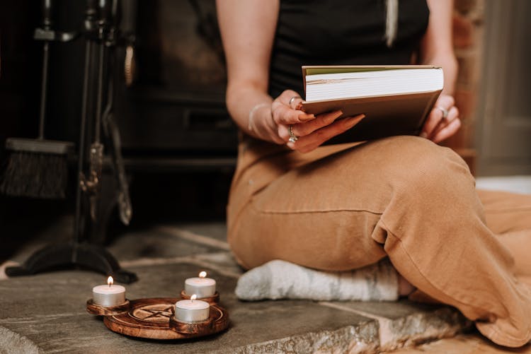 Witch Opening Book Near Pentagram Sign And Sparkling Candles