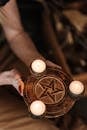 From above of crop anonymous female with pentagram symbol and sparkling candles on blurred background