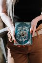 Crop anonymous female with long nails demonstrating antique magic book in hands in daylight