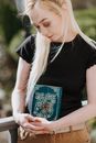Young soothsayer embracing magic book in terrace