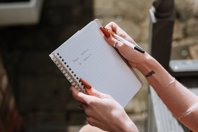 Woman Reading Motivation Words From Dreams To Reality In Copybook