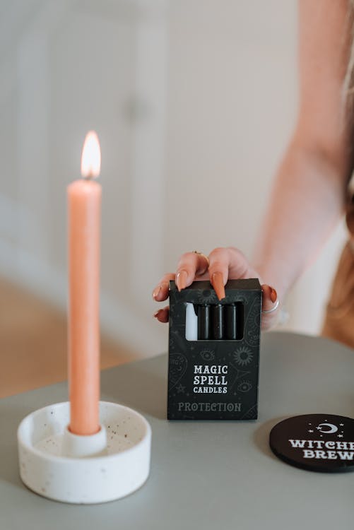 Enchantress touching package with magic spell candles at table