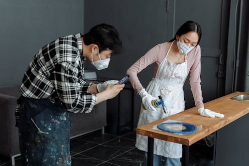 Woman and Man in Masks Working by Table