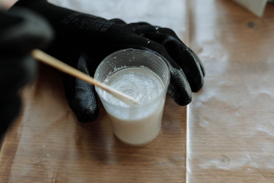 Gloved hands mixing two-part resin in a measuring cup