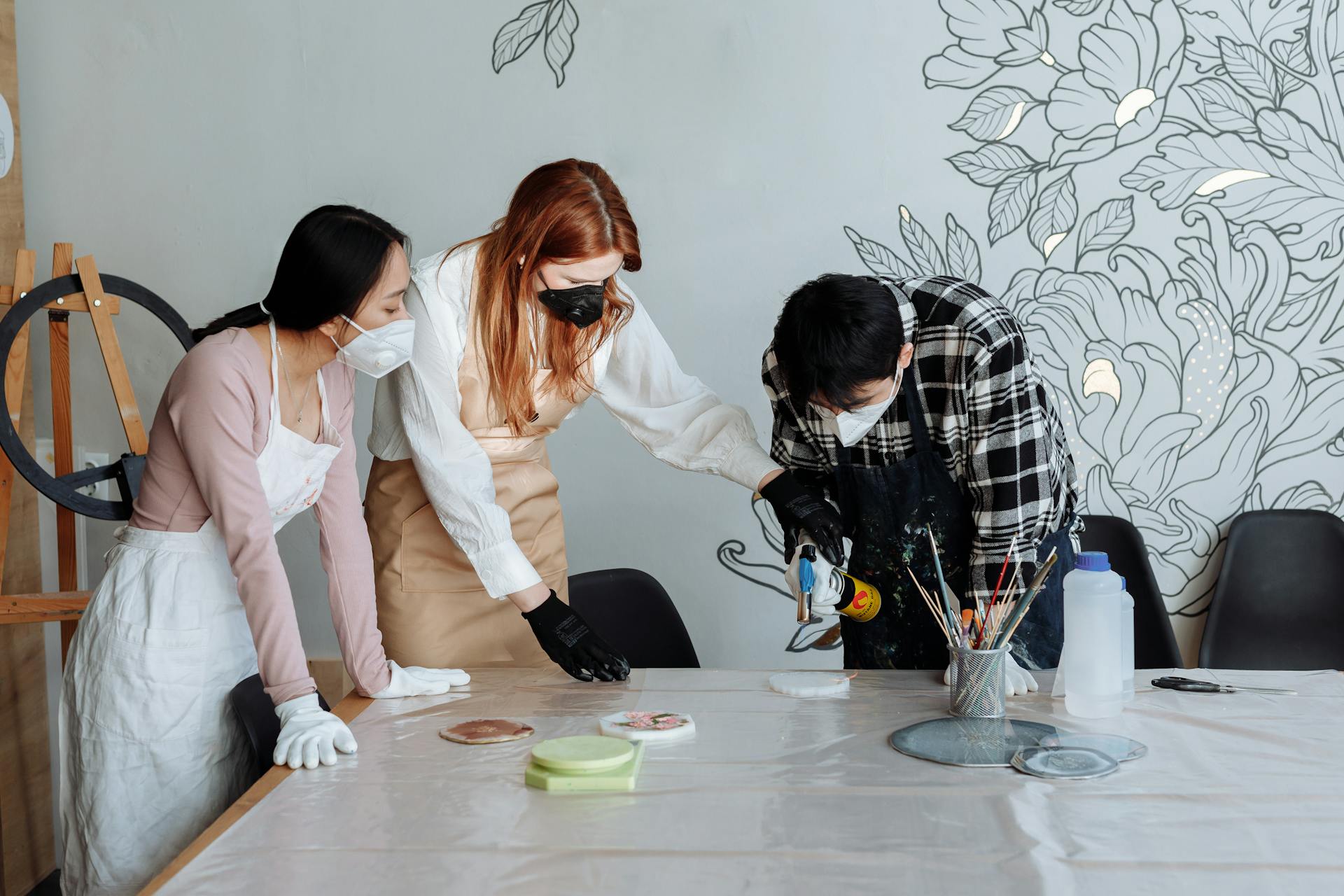 Group of adults crafting with resin in a workshop setting, using safety gear.