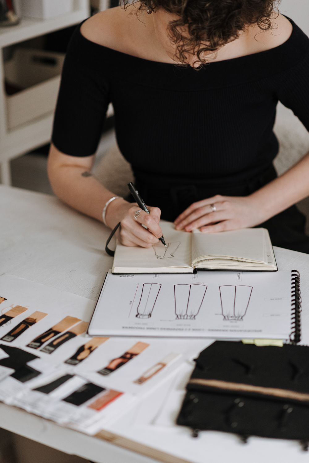 Designer sketching garments with fabric samples