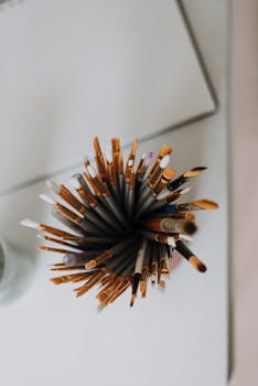 Artistic top view of various paintbrushes in a holder on a desk, perfect for creative projects.
