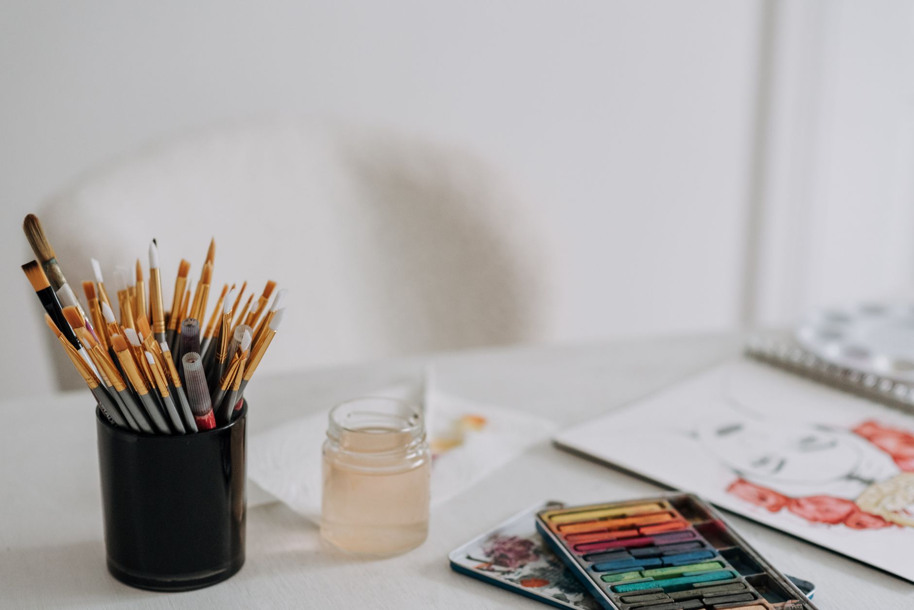 Paintbrushes, watercolours and a sketch on a table