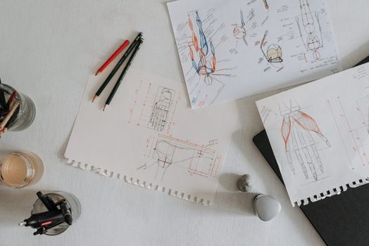 Top view of anatomical sketches with drawing tools on a desk, showcasing artistic process.