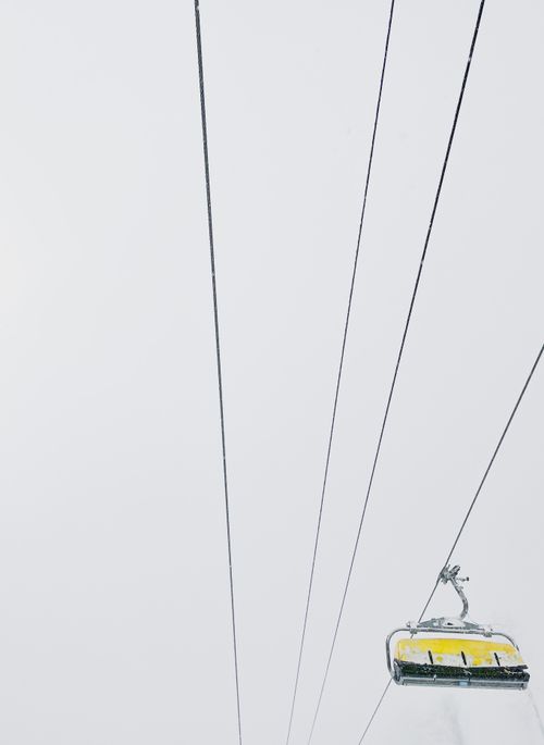 Free A foggy ski lift with yellow chairs moving through a mountainous region, creating a serene and minimalist scene. Stock Photo