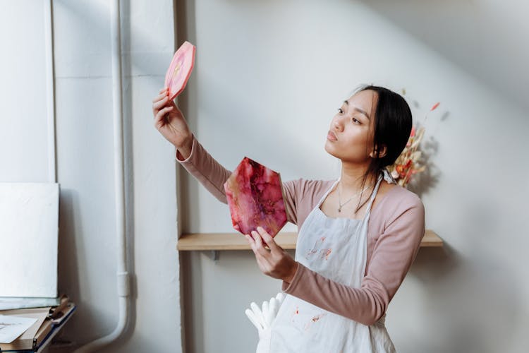 A Woman Holding A Resin Art While Comparing It