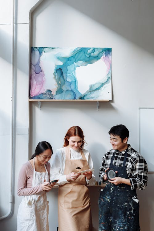 Smiling Women and Man Standing under Painting on Wall
