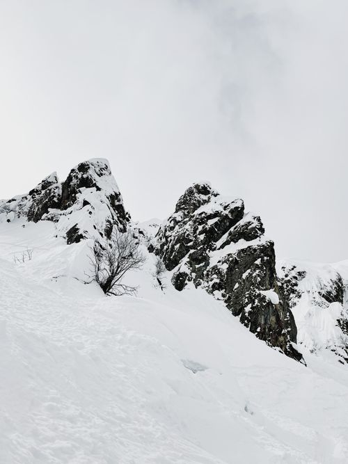 Free Majestic snow-covered rocky mountain with white sky in winter season, perfect for nature and landscape themes. Stock Photo