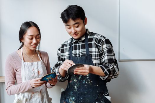 A couple in aprons creating resin art coasters indoors, showcasing creativity and teamwork.