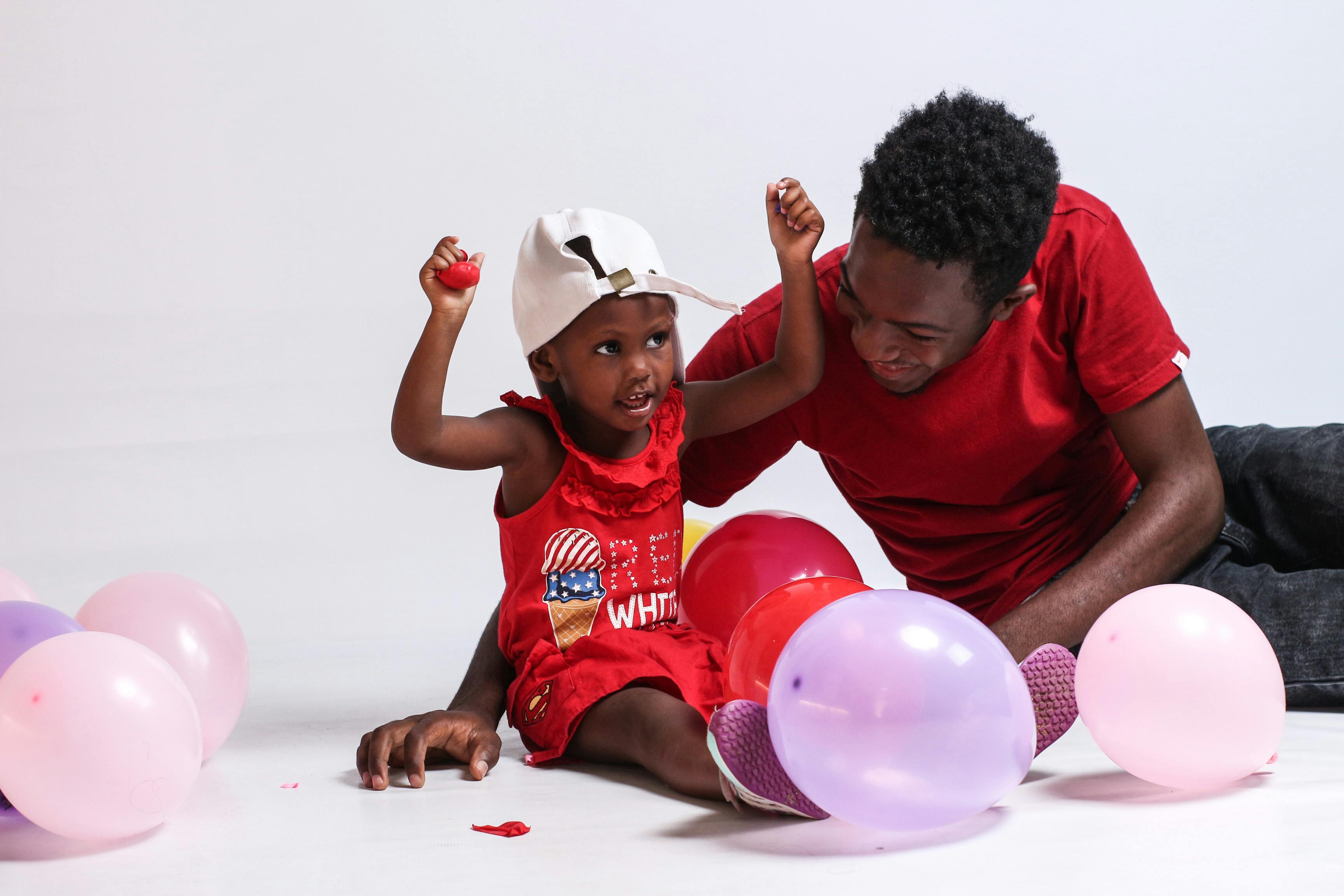 a man in red shirt playing with her daughter in red dress