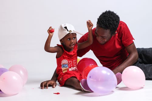 Free A Man in Red Shirt Playing with Her Daughter in Red Dress Stock Photo