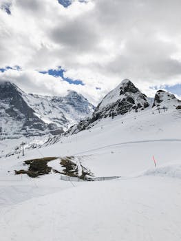 Stunning view of snow-covered mountains and dramatic clouds, showcasing winter beauty.