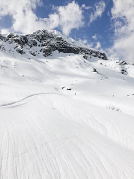 Scenic view of a snow-capped mountain under a bright blue sky with clouds.