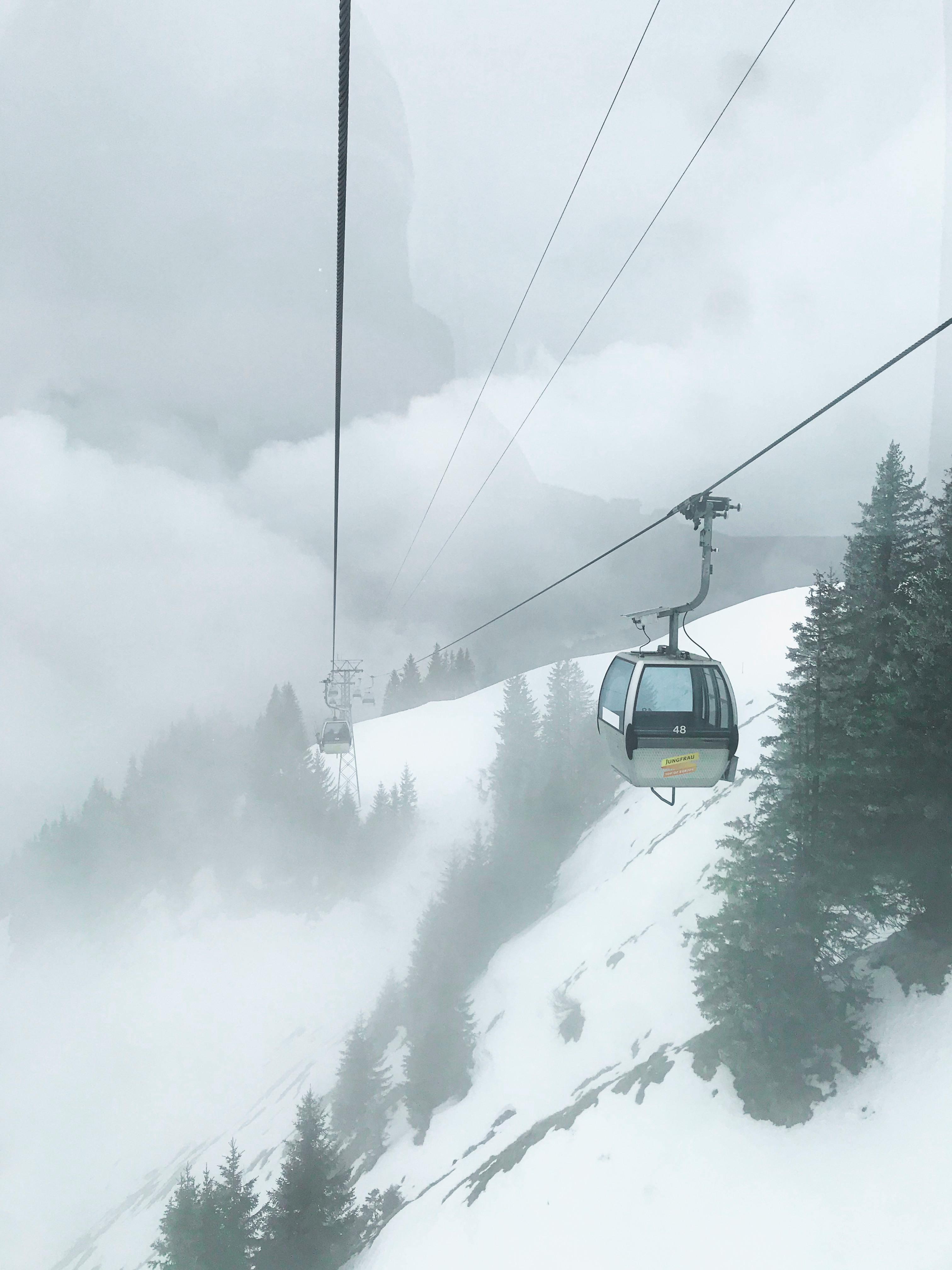 Prescription Goggle Inserts - A scenic view of a cable car traveling through snowy mountains on a foggy winter day.