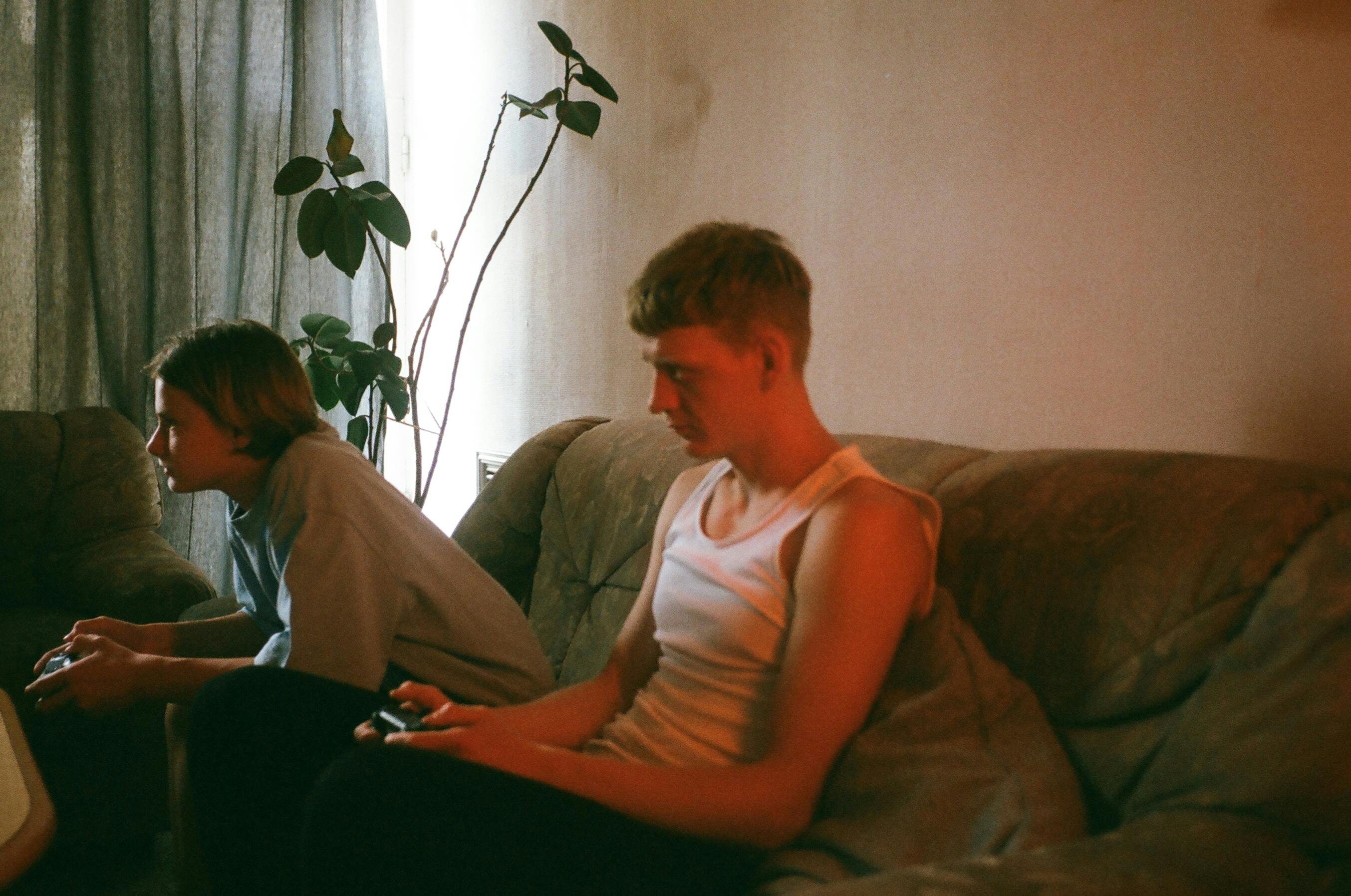 teenage boy and man siiting on a couch and playing video games