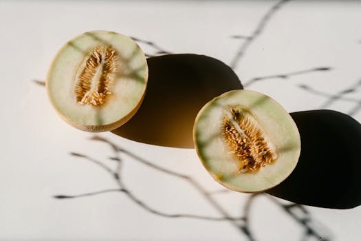 A creative still life photo of cantaloupe halves with artistic shadows, ideal for food photography.