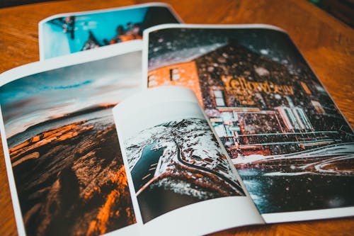 From above of photos with coast and brick house in snow placed on wooden table