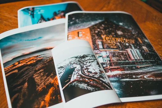 From above of photos with coast and brick house in snow placed on wooden table
