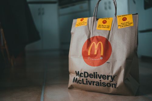 Free Beige package with bright yellow stickers and fast food on floor of apartment on blurred background Stock Photo