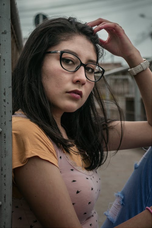 Photo of a Woman in an Orange Shirt Wearing Black Framed Eyeglasses