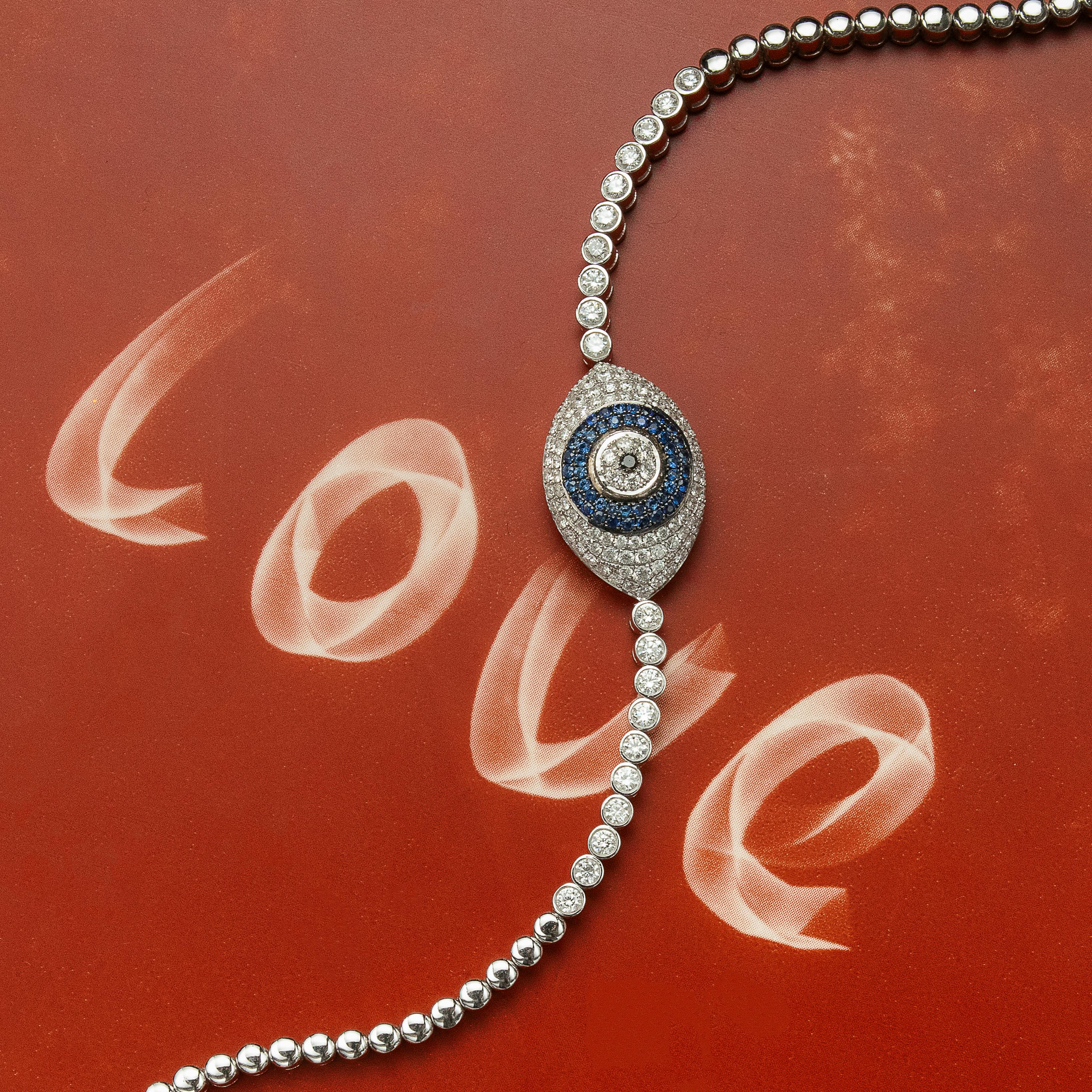 Stunning diamond and sapphire evil eye bracelet displayed on a background with the word 'love'.