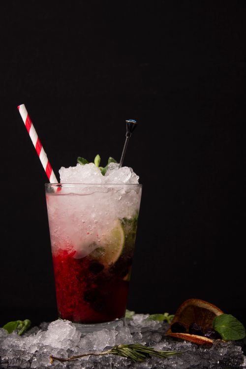 Free Close-up of a vibrant red cocktail with crushed ice and citrus slices, perfect for summer drinks. Stock Photo