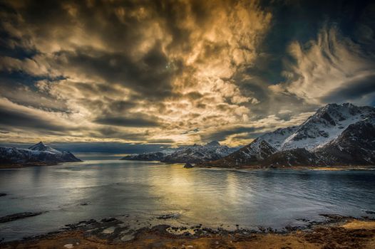Stunning view of Nordland, Norway with dramatic clouds and snow-capped mountains.