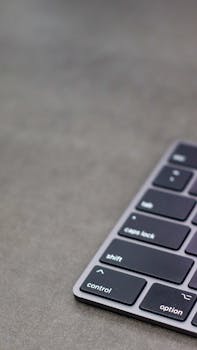 Vertical shot of a sleek modern keyboard on a grey surface, showcasing clean design.