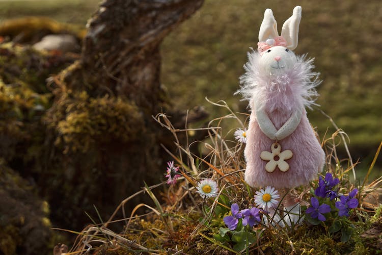 Pink Rabbit Plush Toy On Grass Near Flowers 