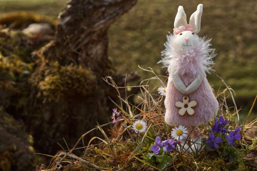 Free Adorable plush rabbit toy in a garden surrounded by vibrant daisies and violets. Stock Photo