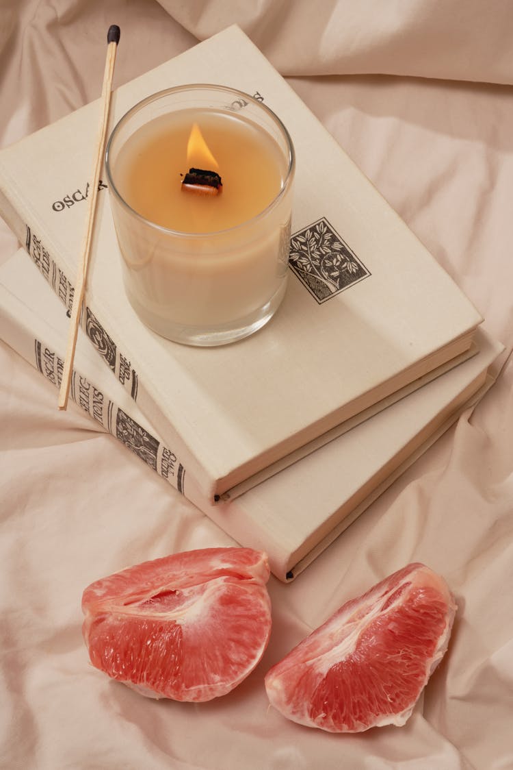 Aroma Candles On Books Near Grapefruit